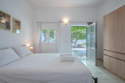 een slaapkamer met een groot wit bed en een glazen schuifdeur bij Vrisidia Cottage - Nature, Seaview & Relax in Plakias