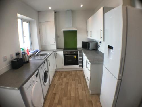 a kitchen with white cabinets and a white refrigerator at The Attic En-suite Room in Plymouth