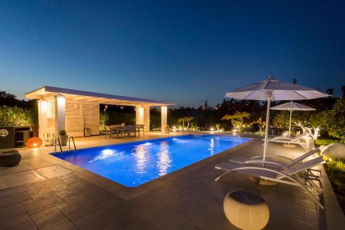 a swimming pool with an umbrella and a patio at Antigone Estate in Koskinou