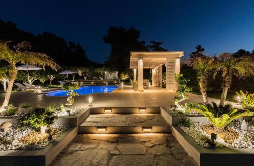 a courtyard with a swimming pool at night at Antigone Estate in Koskinou