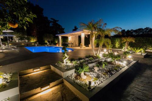 a backyard with a swimming pool and a garden at night at Antigone Estate in Koskinou