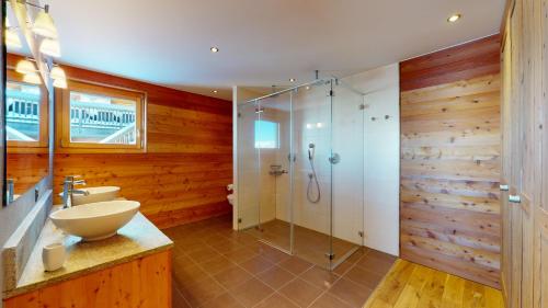 La salle de bains est pourvue d'une douche en verre et d'un lavabo. dans l'établissement Egg SAUNA & LUXURY chalet 16 pers by Alpvision Résidences, à Veysonnaz