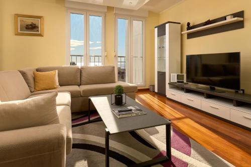 a living room with a couch and a tv at Sun Spalato Hills 7 in Split