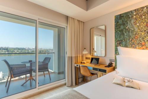 a hotel room with a bed and a desk and a balcony at Pestana Douro Riverside - Preferred Hotels & Resorts, Lifestyle in Porto