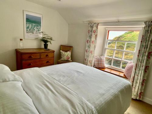 a bedroom with a white bed and a window at Unique Retreat - 2 bedroom cliff top cottage with large terrace in Portloe