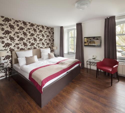 a bedroom with a large bed and a red chair at Boardinghouse Rathsmühle in Aachen