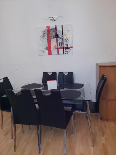 a dining room table with black chairs and a painting at 3-rooms apartment for up to 4 persons near to Prater in Vienna