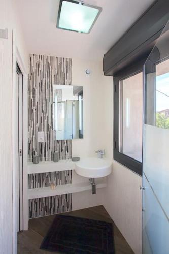 une salle de bain avec un lavabo, un miroir et une fenêtre dans l'établissement Le SAN PETRONE-TOUR EN PIERRE EN CENTRE CORSE ENTRE MER ET MONTAGNE, à Moltifao