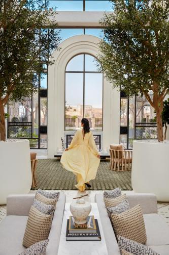 a woman in a yellow dress sitting in a room with windows at Fairmont La Marina Rabat Sale Hotel in Rabat