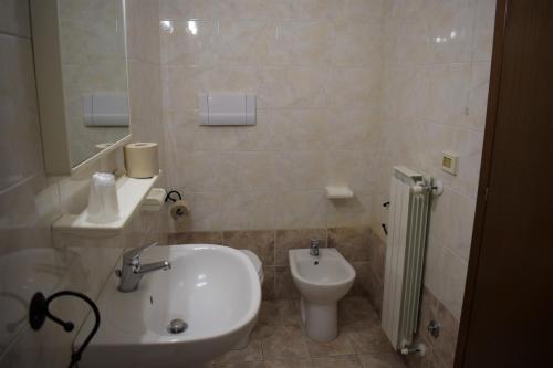 a white bathroom with a sink and a toilet at Hostel il Tetto in Melfi