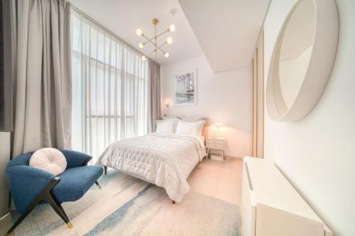 a white bedroom with a bed and a blue chair at Studio with City Views, Jumeirah Lake Towers - Mint Stay in Dubai