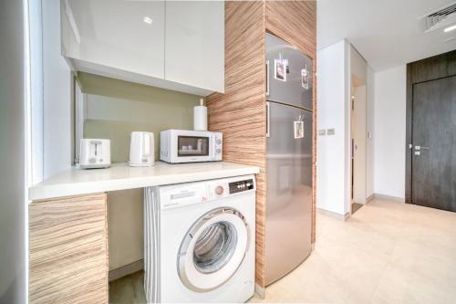 a kitchen with a washing machine and a refrigerator at Studio with City Views, Jumeirah Lake Towers - Mint Stay in Dubai