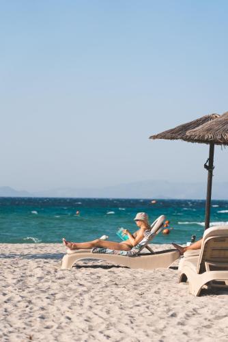 two people sitting in chairs on a beach with an umbrella at Li Mango in Tigaki
