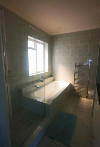 a bathroom with a bath tub and a window at Neptunes Seat - Garden Paradise with Ocean Views in Cape Town