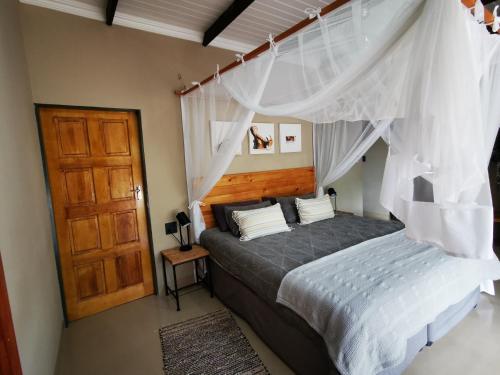 a bedroom with a bed with a canopy at Ostrich Hide in Marloth Park