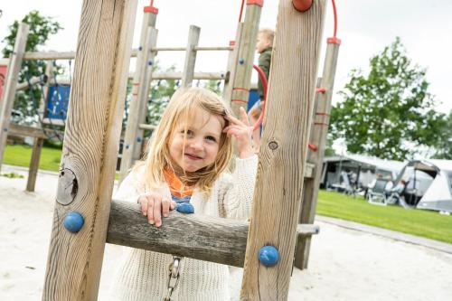 een klein meisje op een glijbaan in een speeltuin bij Recreatiepark De Lucht in Renswoude