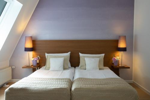 a bedroom with a large white bed with two lamps at Hotel Lindenhof in Wittlich