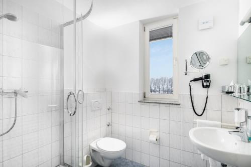 a white bathroom with a toilet and a sink at Hotel Classic in Freiburg im Breisgau