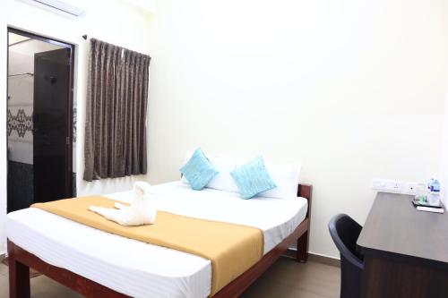 Cette chambre comprend un lit et un bureau. dans l'établissement Elite Inn, à Pondichéry