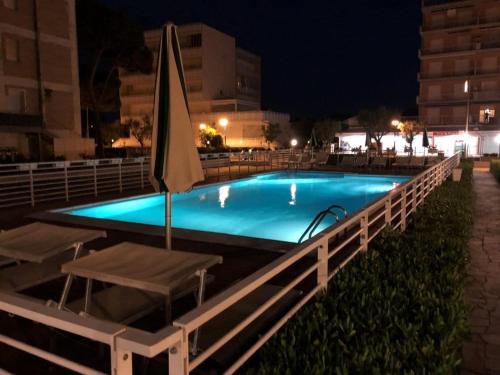 una piscina por la noche con sombrilla y sillas en Hotel Lima, en Lido di Savio