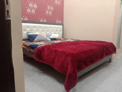 a bedroom with a bed with a red blanket on it at The Jay Hotel By WB Inn in Rāe Bareli
