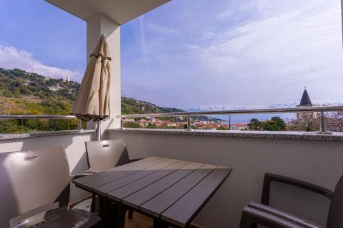 a balcony with a wooden table and chairs and a window at Apartments Crnekovic Tomislava 8 in Baška