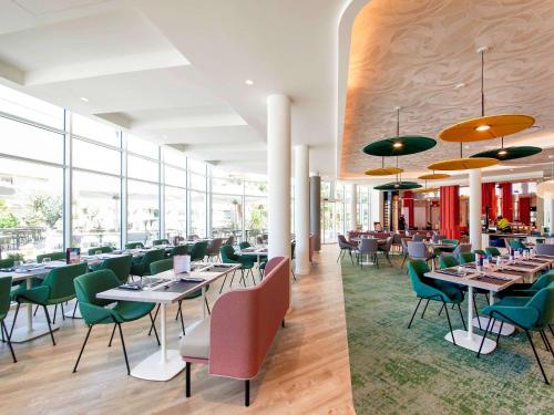 a restaurant with tables and chairs and windows at Novotel Clermont-Ferrand in Clermont-Ferrand