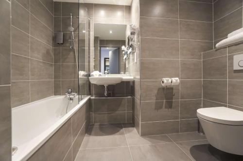 a bathroom with a sink and a toilet and a tub at Best Western Plus Hotel Du Parc Chantilly in Chantilly