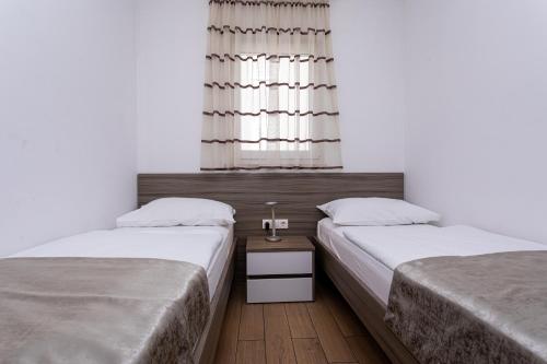 two twin beds in a room with a window at Apartments Crnekovic Tomislava 8 in Baška