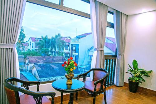 a room with a table and chairs and a large window at Green Sand Homestay in Hoi An