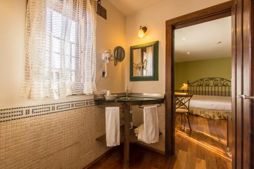 a bathroom with a sink and a mirror and a bed at El Rincón de Rascafría in Rascafría