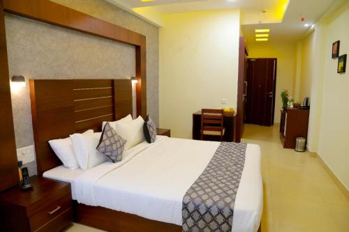 a bedroom with a large white bed in a room at CLUB 99 SUITES in Kakkanad