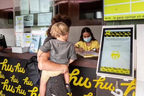 a woman wearing a face mask standing at a cash register at hu Roma Camping In Town in Rome