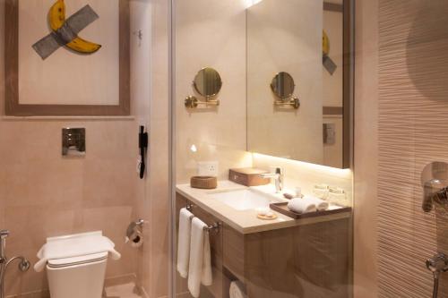 a bathroom with a sink and a toilet and a mirror at The Greenwood Guwahati - A Luxury Boutique Hotel in Guwahati