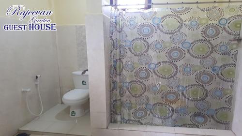 a bathroom with a shower curtain with a toilet at Rajeevan Garden Guest House in Jaffna
