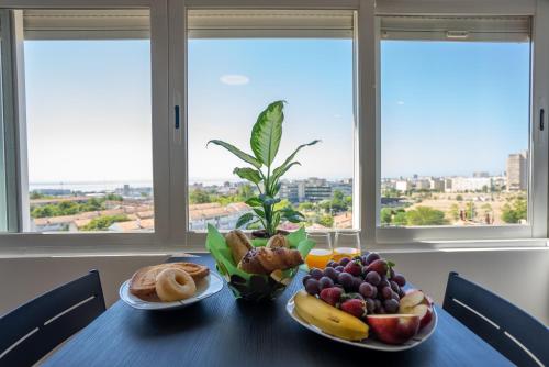 a table with two plates of fruit and bread on it at Olivais Apartment River View in Lisbon