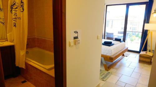 un bagno con una camera da letto con vasca e un letto di Apartment DECORA Sea View a Topola