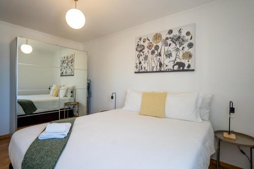 a bedroom with a large white bed with a mirror at Olivais Apartment River View in Lisbon