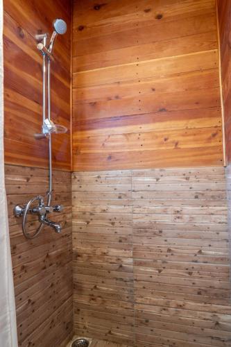 a bathroom with a shower with wooden walls at Le ROI Floating Huts & Eco Rooms Tehri in Tehri-Garhwāl