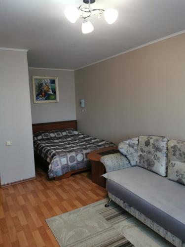 sala de estar con sofá y cama en 1 комнатная квартира в самом центре с видом на сквер en Kostanái