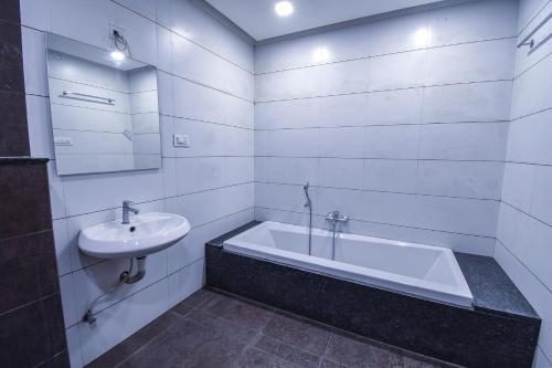 Baño blanco con bañera y lavamanos en Hotel Ravikiran, en Kolhapur