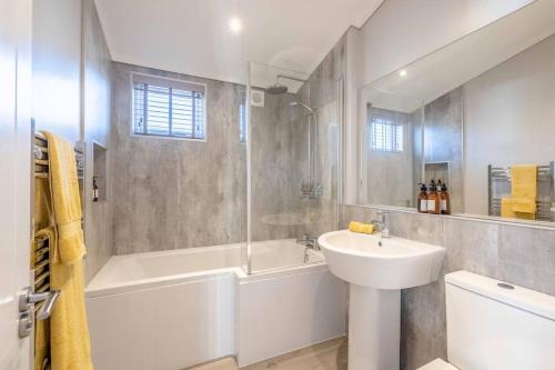 ein weißes Badezimmer mit einer Badewanne und einem Waschbecken in der Unterkunft Stylish Lodge At Windsor Racecourse Marina in Windsor