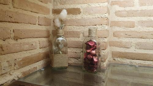 two glass bottles on a brick wall with flowers in them at El Rincón de Rascafría in Rascafría