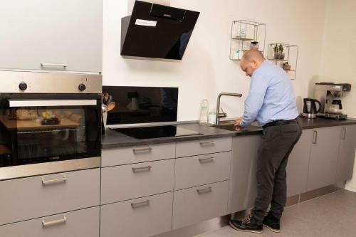 a man standing in a kitchen with a sink at Hvide Sande Inn in Hvide Sande