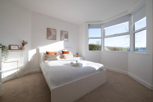 a white bedroom with a bed and a window at Hampton House - Sleeps 7 - Free Parking and WiFi in Bristol