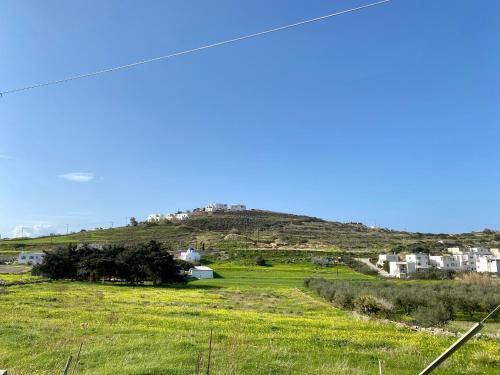a green field with a hill in the background at Olive House Apartment Paros in Kampos Paros
