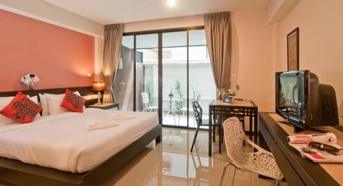 a bedroom with a bed and a desk with a tv at Ratana Residence Thalang in Thalang