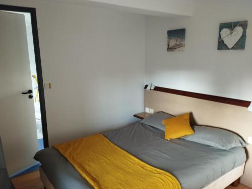 um quarto com uma cama com uma almofada amarela em L'Albatros em Perros-Guirec