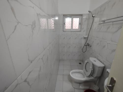 a white bathroom with a toilet and a window at Villa N'KOMI in Lomé