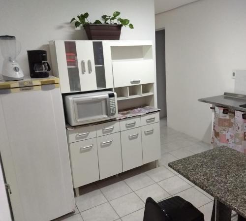 y cocina con nevera y microondas. en casa da Lú, en Florianópolis